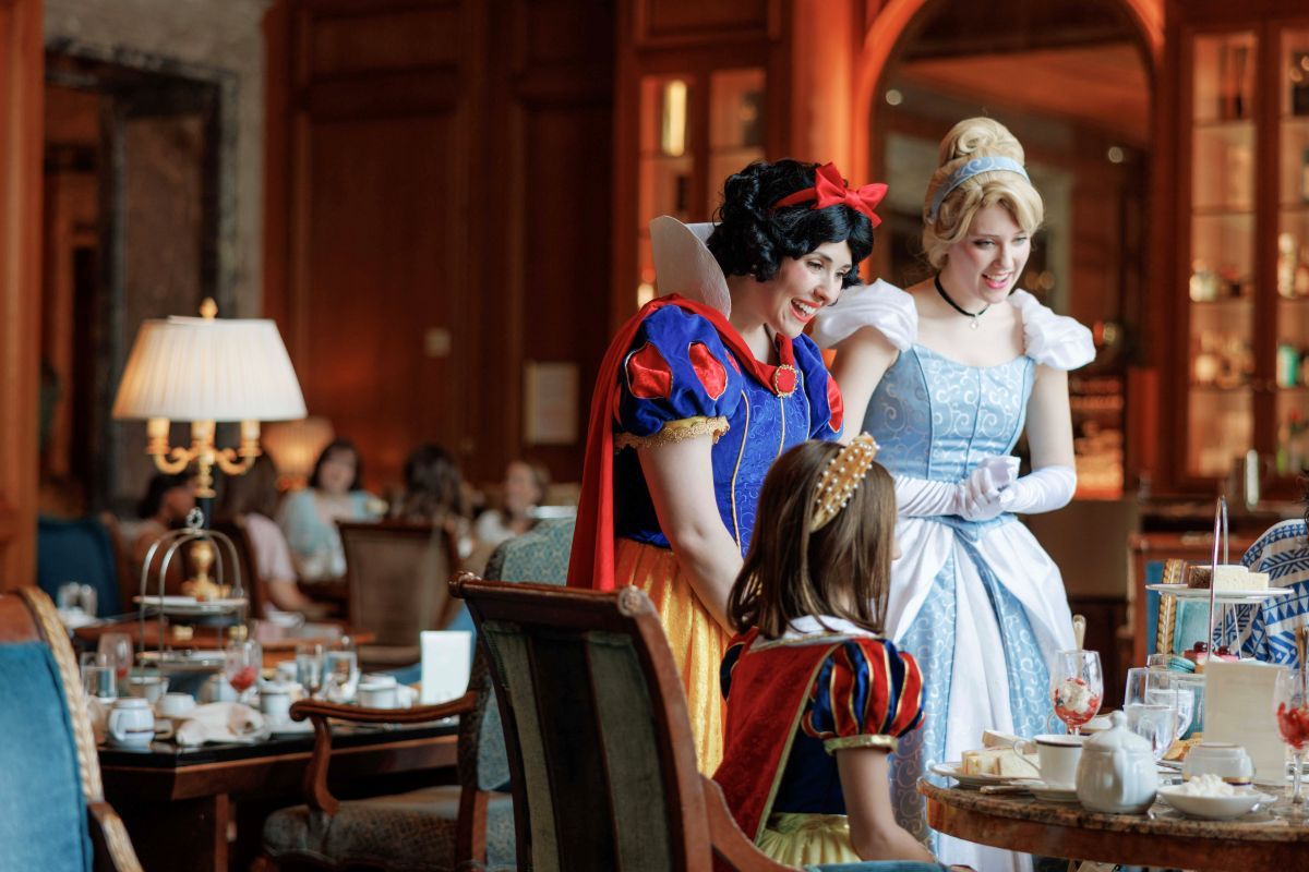 Snow White and Cinderella visiting a table with a little girl during tea