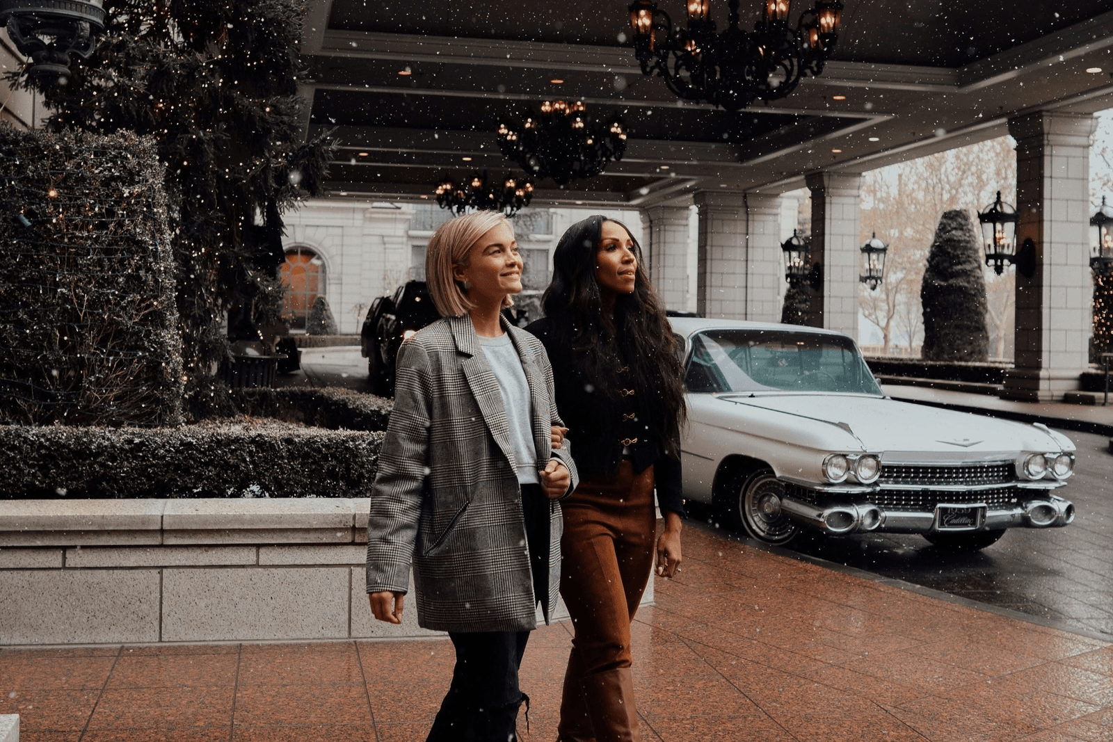 Two women walk across the hotel front drive