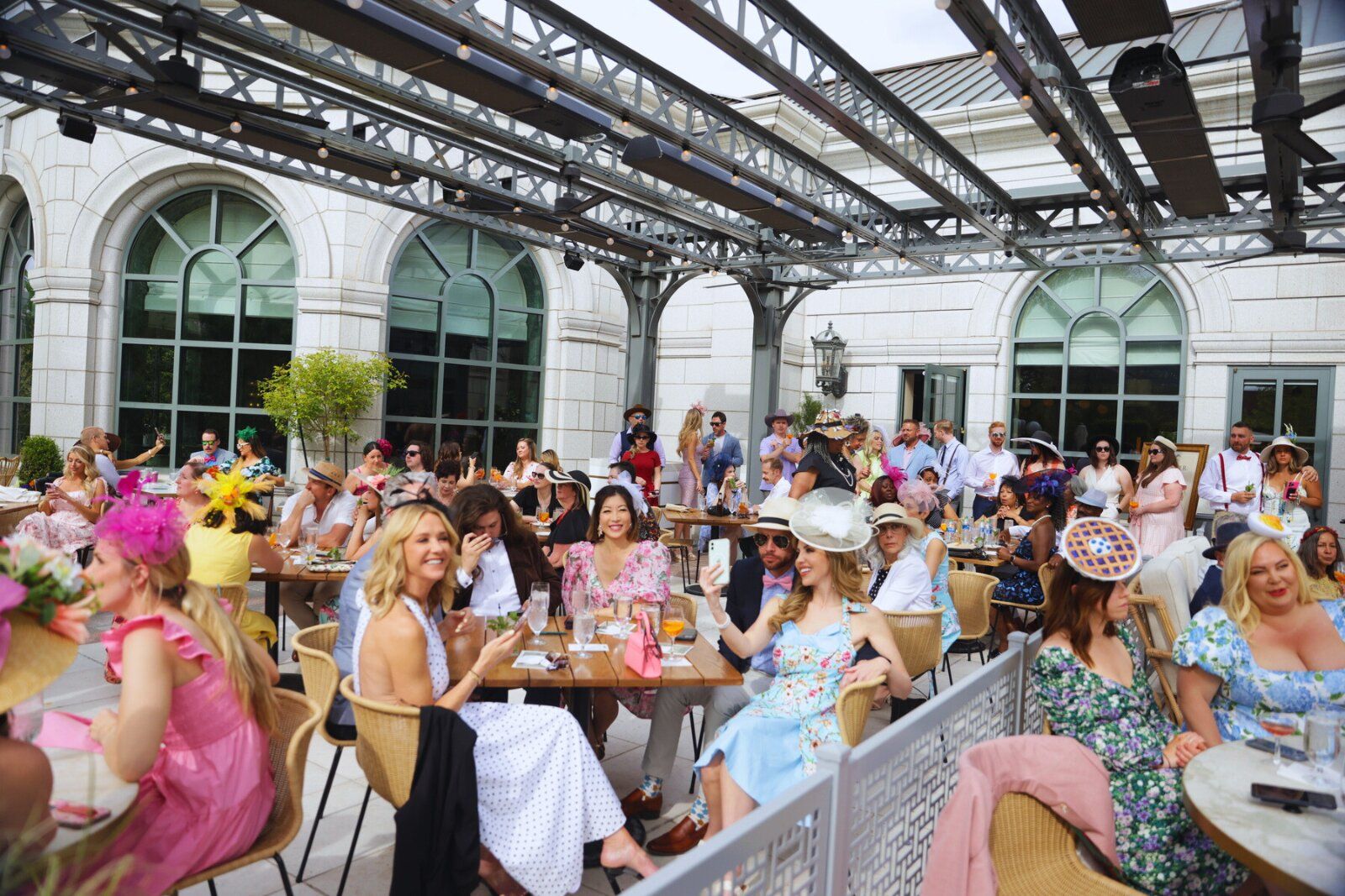 group of people sitting on an outside patios at tables wearing Churchill Downs themed attire