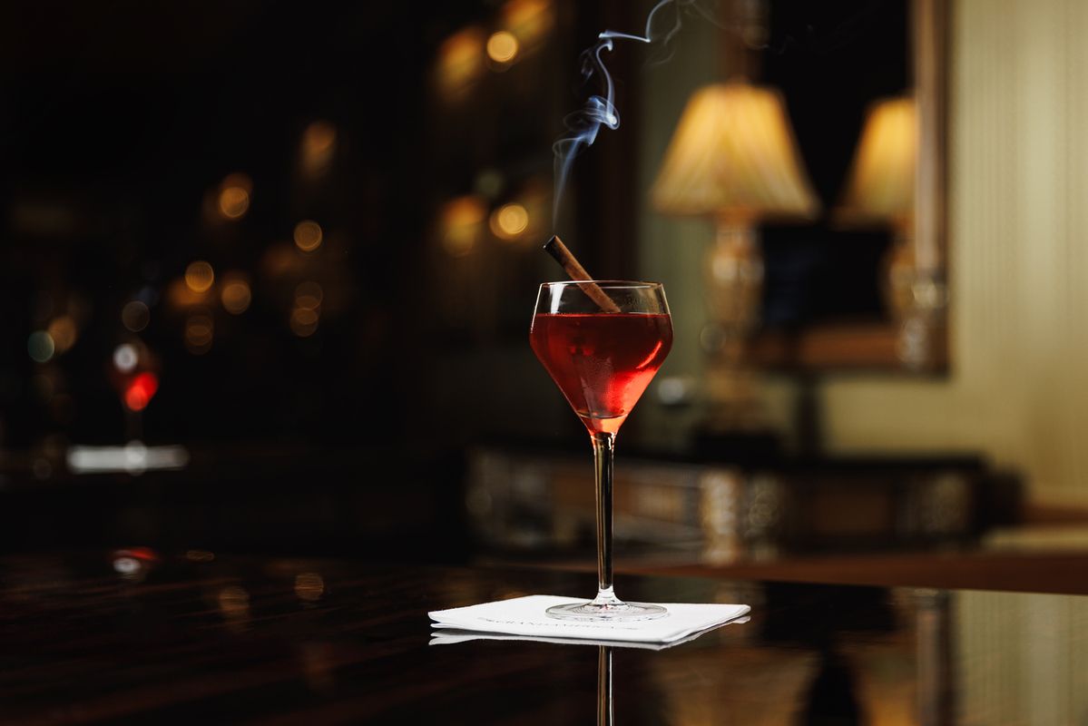 halloween themed cocktail with smoking cinnamon stick
