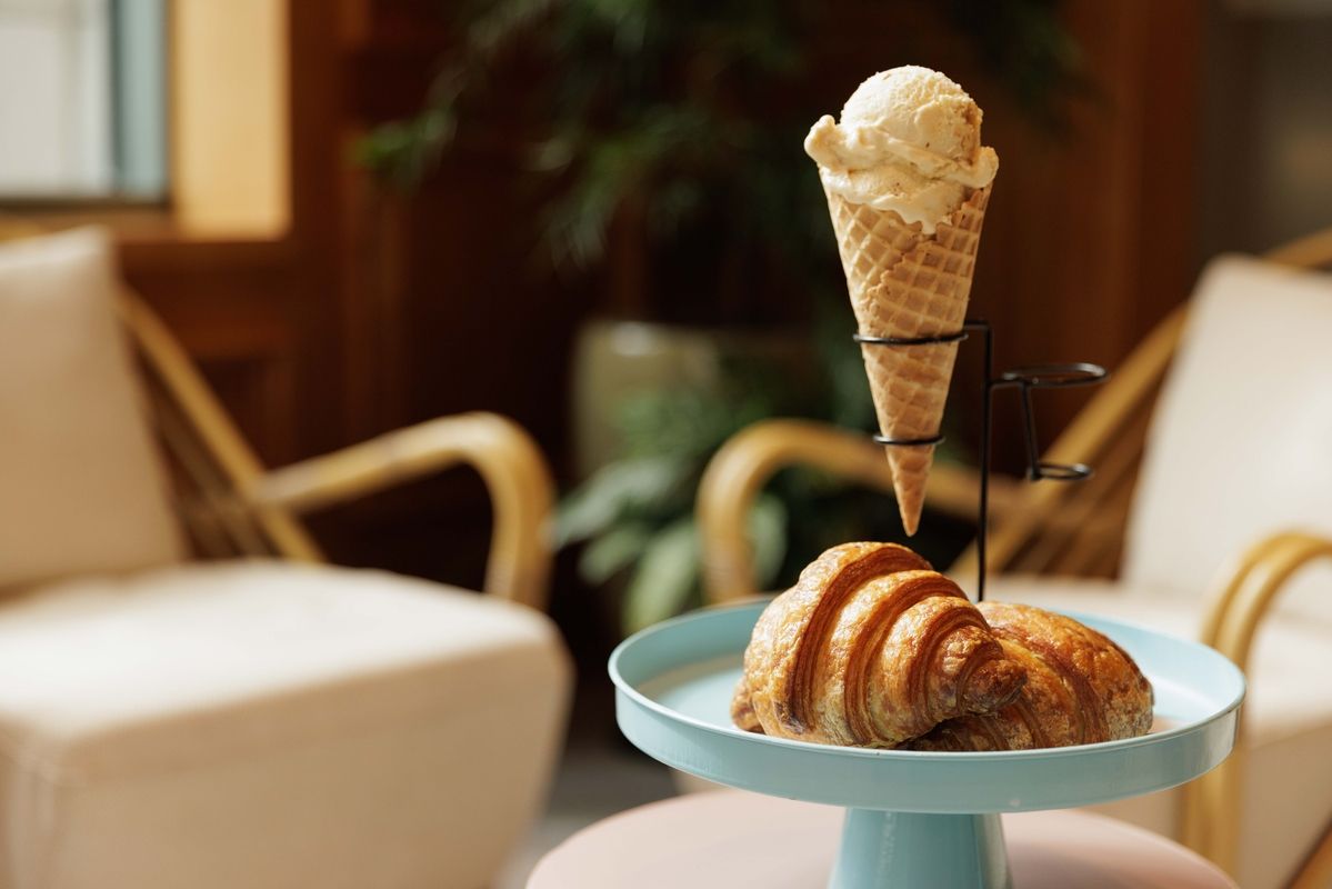 ice cream in a cone in a stand next to a plate with a croissant