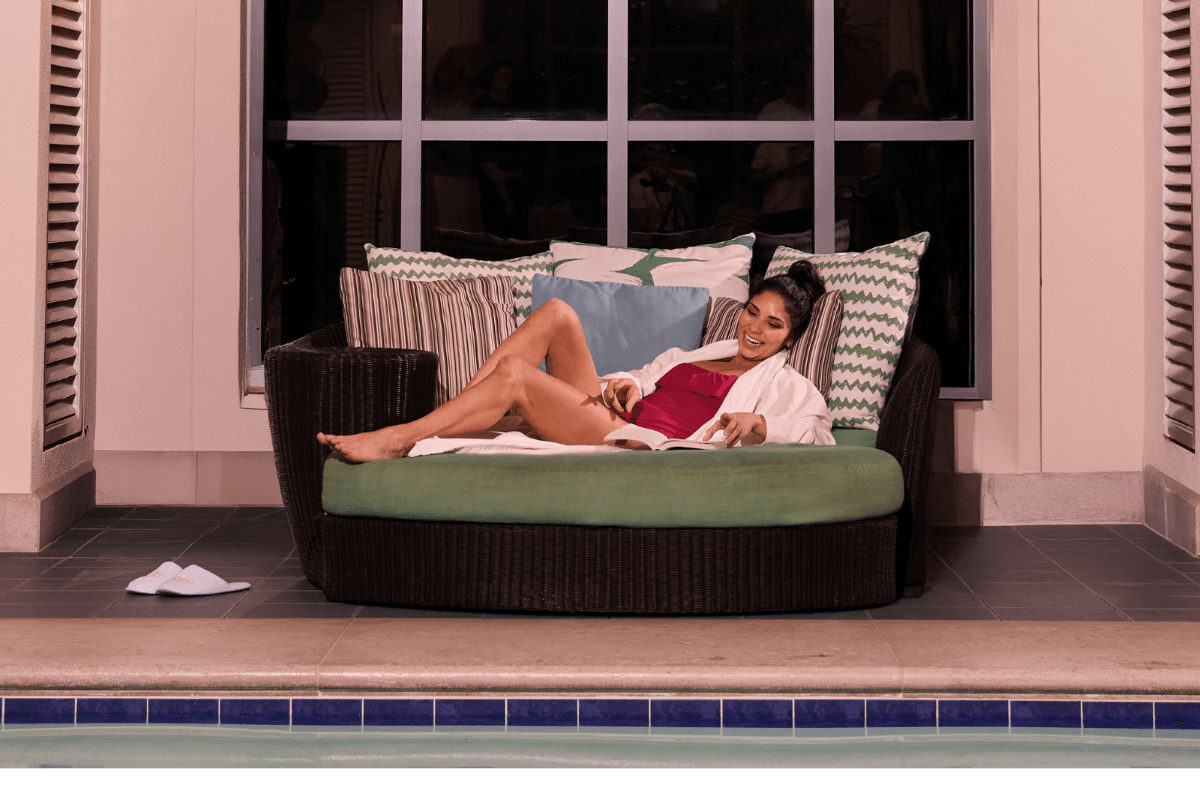 woman reading a book next to the indoor pool while laying on a lounge chair