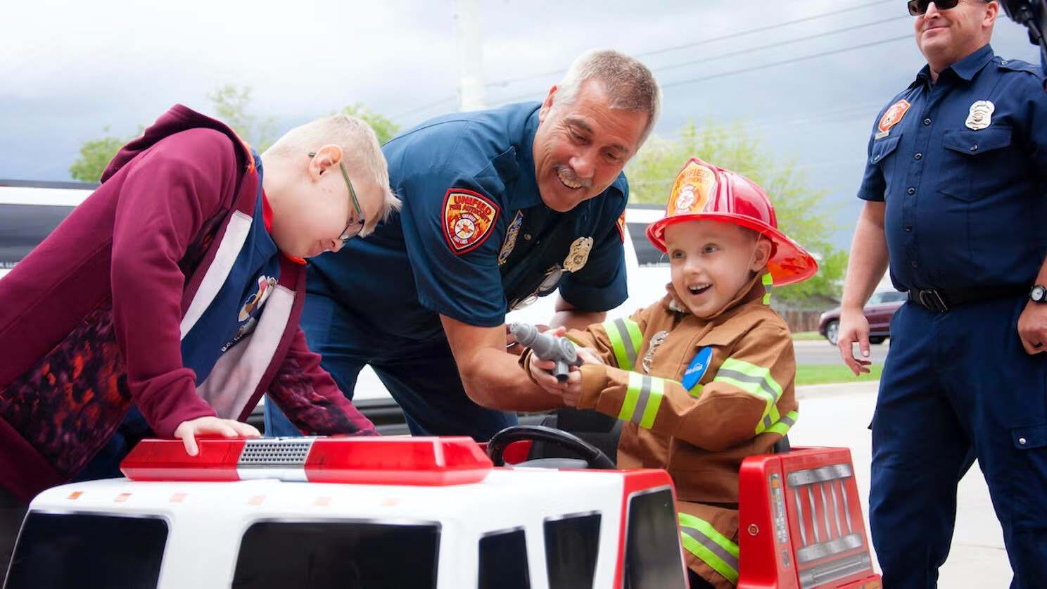 Make-A-Wish Utah photo of a little boy working with firefighters