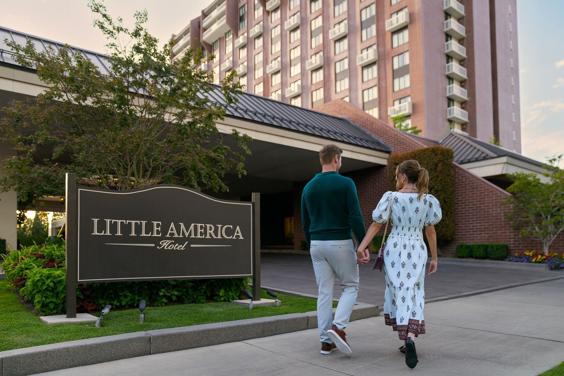 A couple walking in front of Little America sign