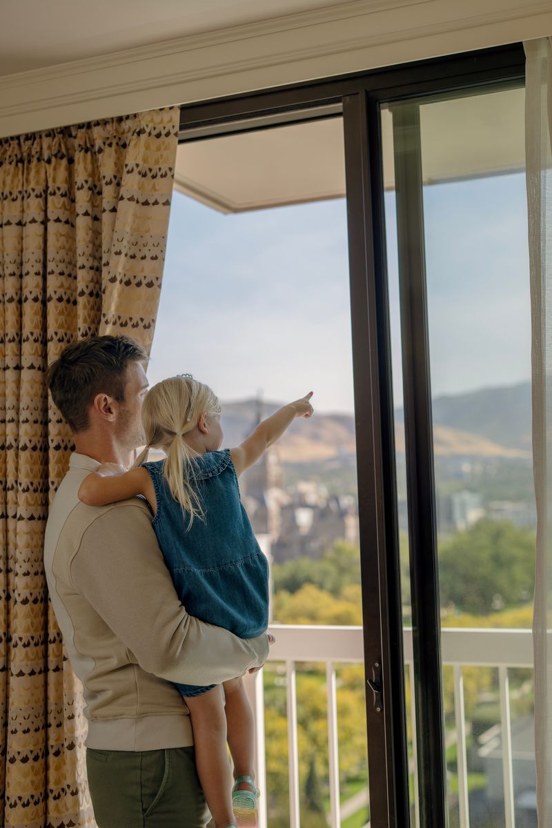father holding daughter looking out of a window