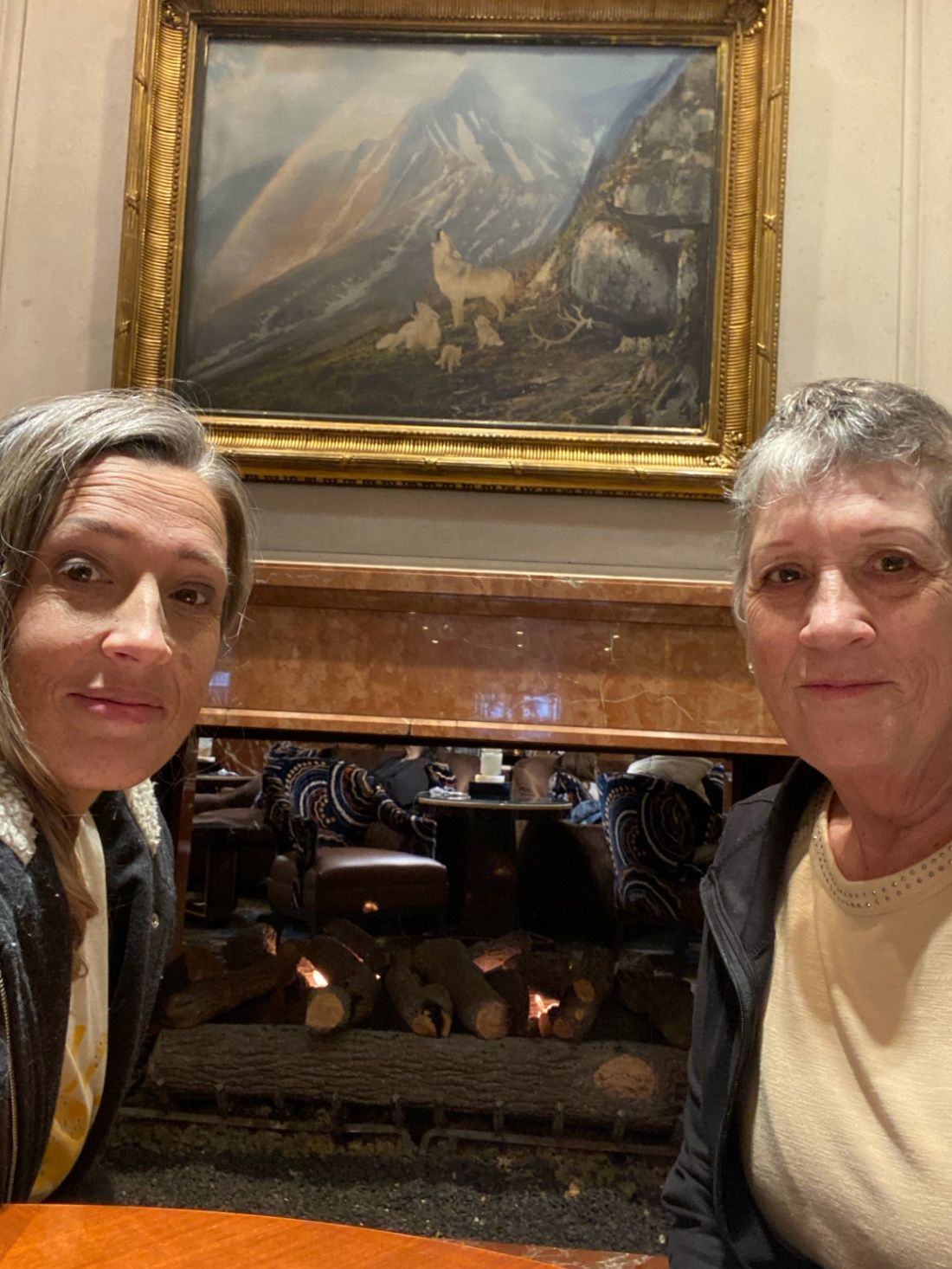 Two women selfie in front of Little America lobby fireplace.