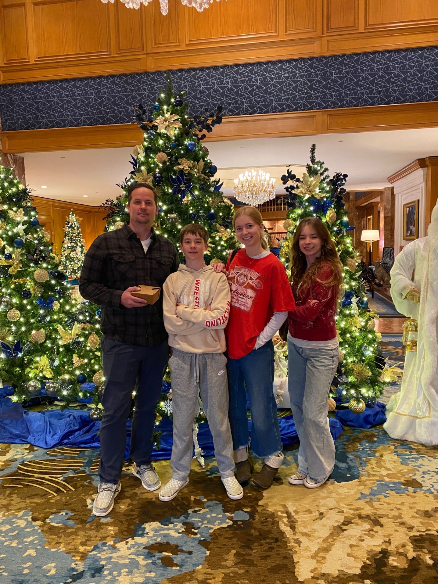 family posing in front of christmas trees