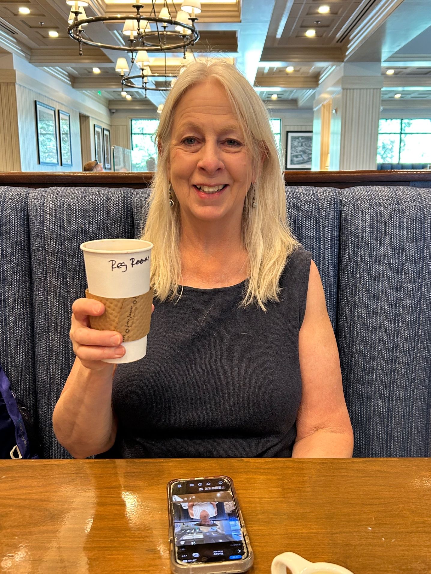 Woman holding up a coffee cup at ta booth at the coffee shop
