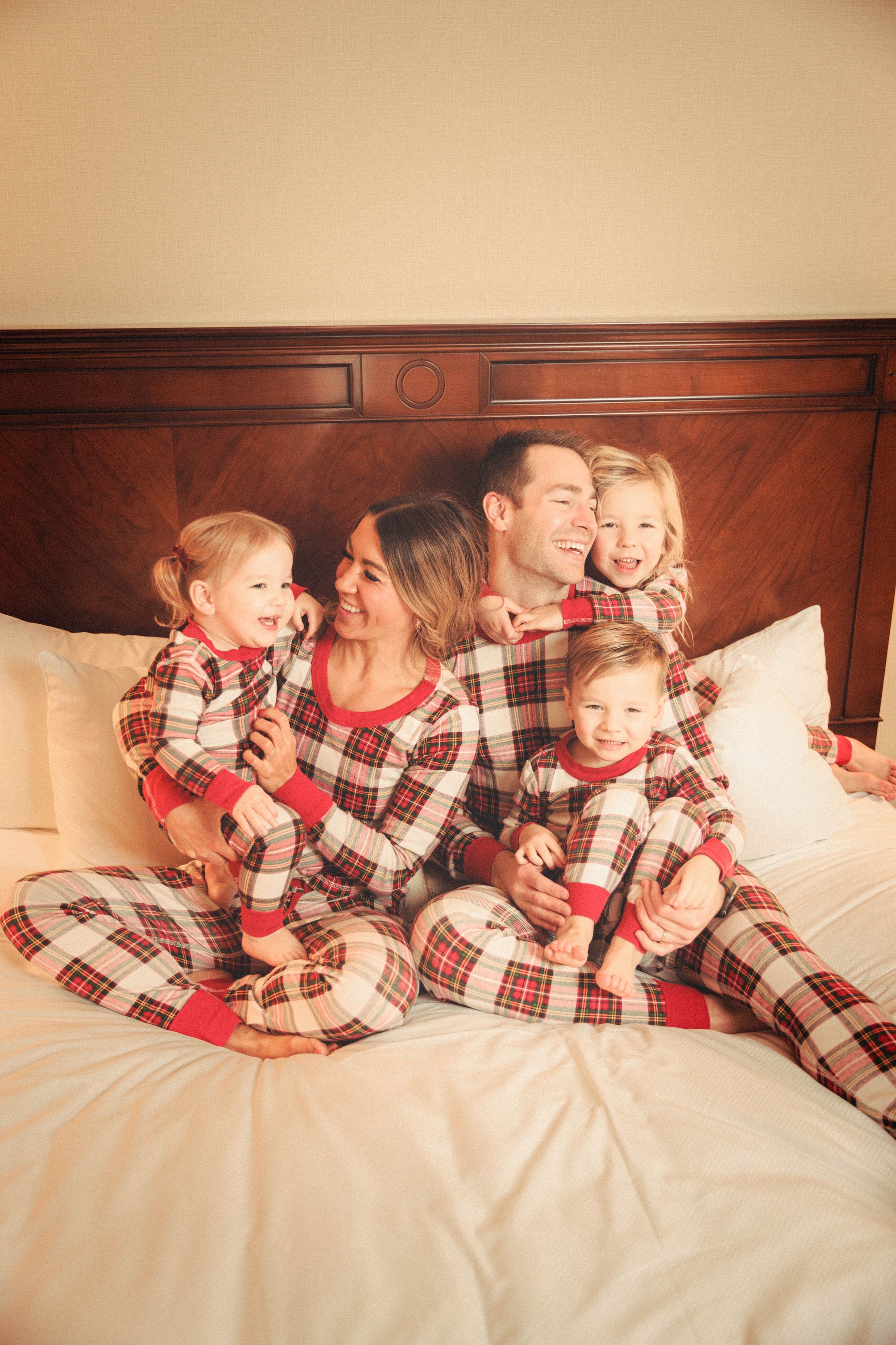 family in matching pajamas laughing together in bed