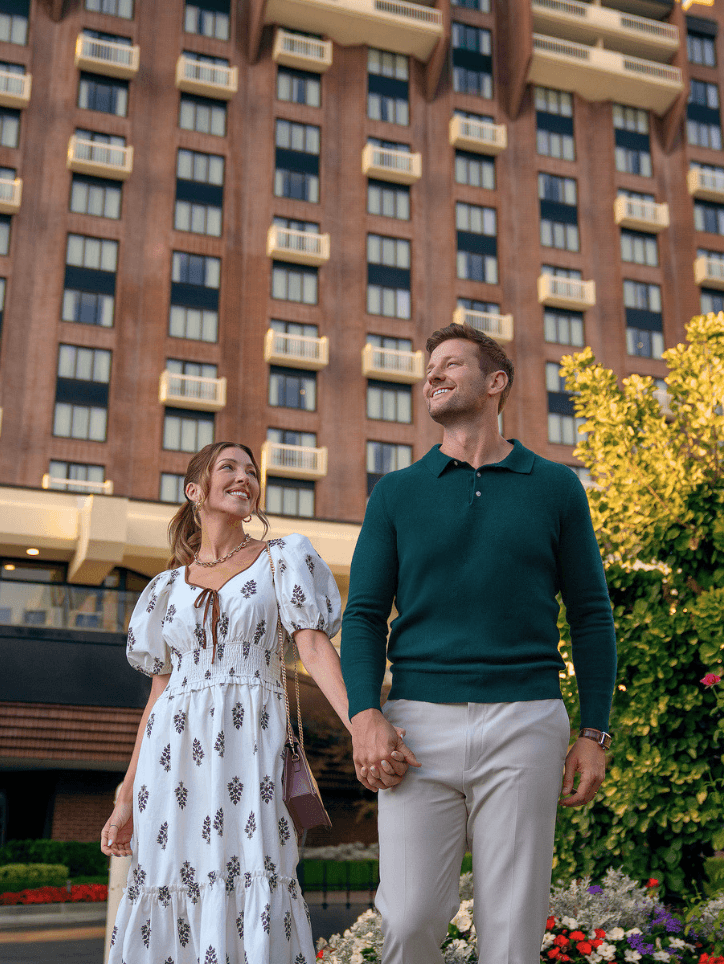 Couple holding hands while standing outside of Little America Hotel